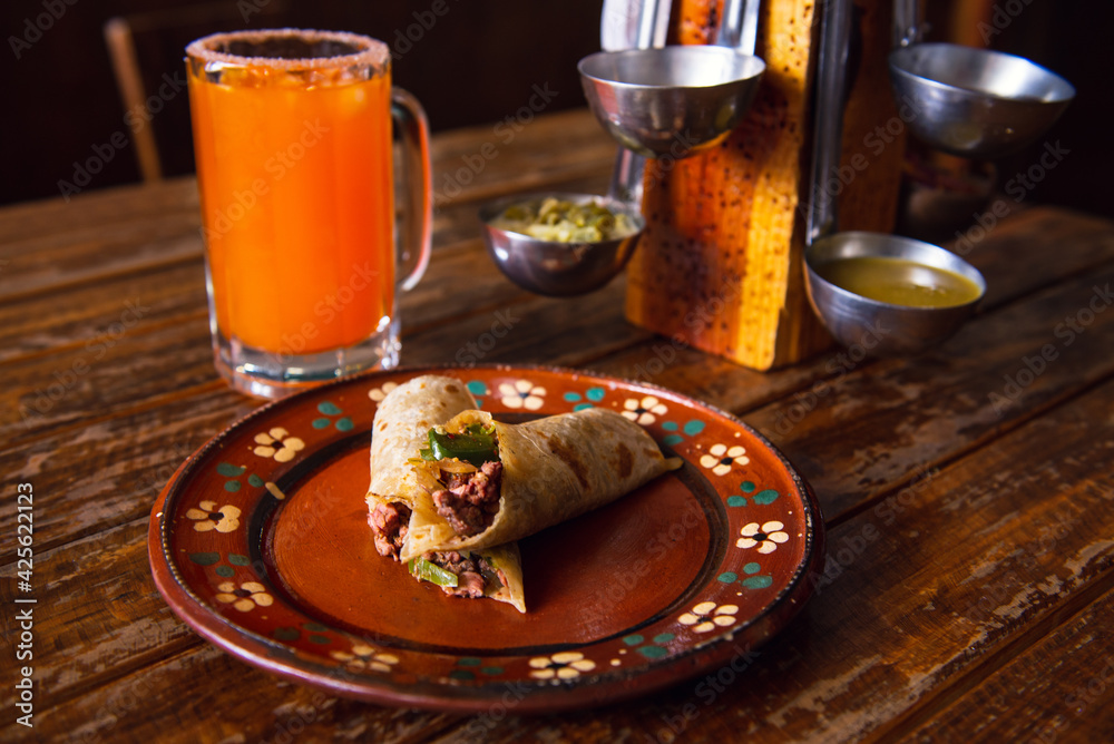 Mexican burrito and michelada beer with tomato juice with copy space
