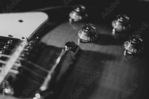 Czarno białe zdjęcie, zbliżenie na gitarę. Struny i przełączniki - detale instrumentu muzycznego