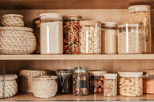Organizing zero waste storage in the kitchen. Pasta and cereals in reusable glass containers in kitchen shelf. Sustainable lifestyle idea photo