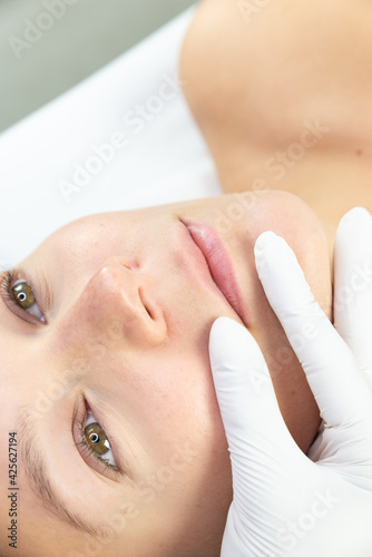 Zbliżenie na usta kobiety w gabinecie kosmetycznym. Zdjęcie przed zabiegiem makijaż permanentny ust. Badanie ust. Salon medycyny estetycznej. 