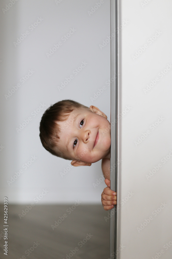 Smiling cute kid peeking from the doorway Smiling cute kid peeking from the doorway