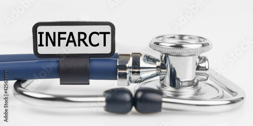 On the white surface lies a stethoscope with a plate with the inscription - INFARCT