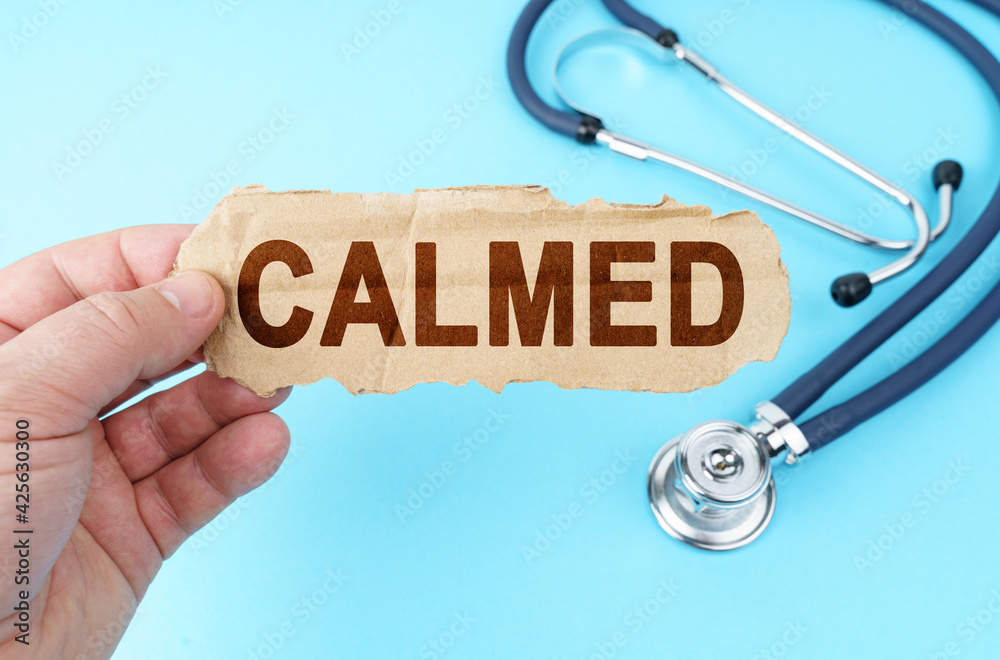 On a blue background, a man holds a cardboard box with the inscription - CALMED On a blue background, a man holds a cardboard box with the inscription - CALMED
