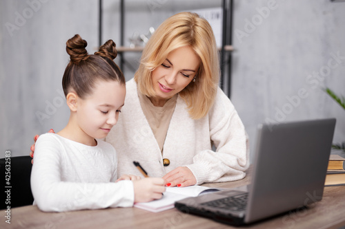 school, homework and distance education concept - happy school girl doing homework with her mother at home