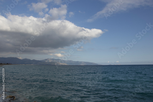 cloudy sky with blue sea stretching along the coastline and mountains stretching towards the sea