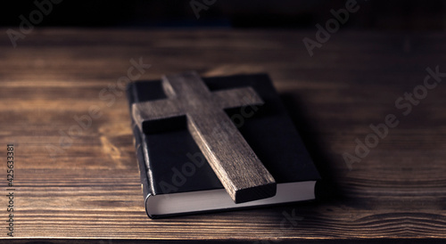 Wooden cross close up. Crucifixion of Jesus. On a closed Bible. On a wooden background