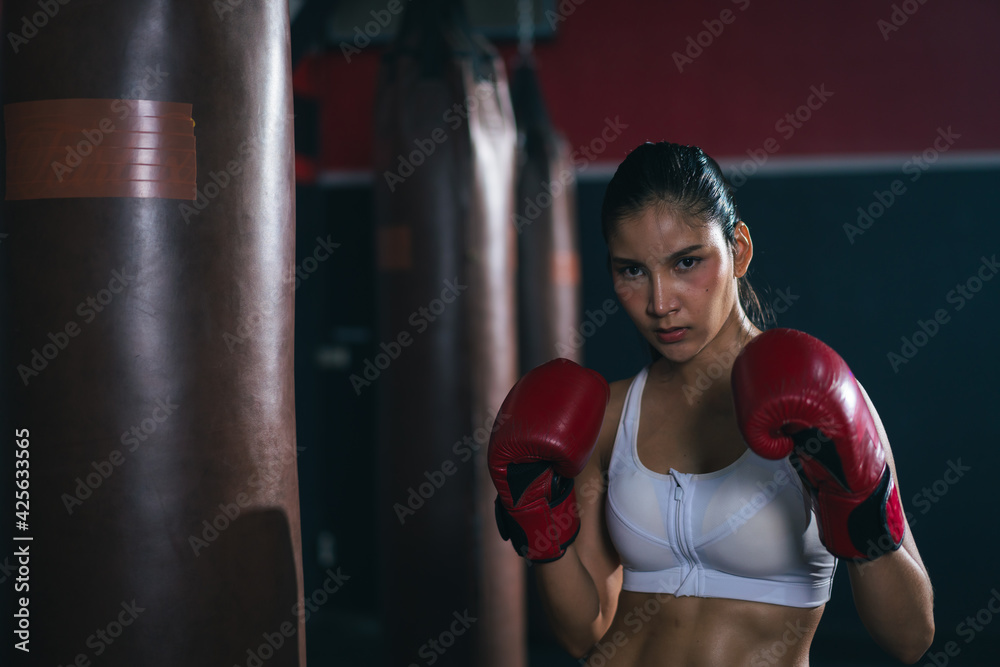 Fototapeta premium Young Asian doing boxing or Muay Thai punching sandbag in fitness club or gym. healthcare and sport concept.