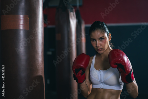 Young Asian doing boxing or Muay Thai punching sandbag in fitness club or gym. healthcare and sport concept.