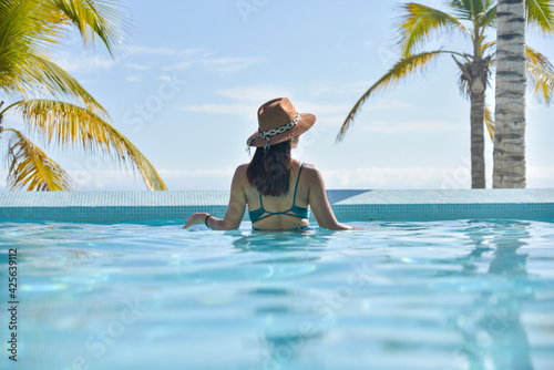 Fototapeta Naklejka Na Ścianę i Meble -  young woman in style fashion and straw hat looking at the beach scenery