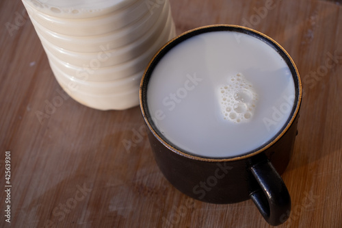 Glass of milk standing on old wooden table. Black glass with white milk. Black glass with white milk on the table