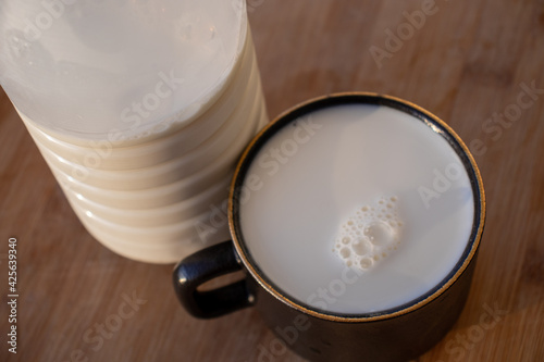 Glass of milk standing on old wooden table. Black glass with white milk. Black glass with white milk on the table