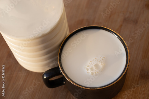 Glass of milk standing on old wooden table. Black glass with white milk. Black glass with white milk on the table