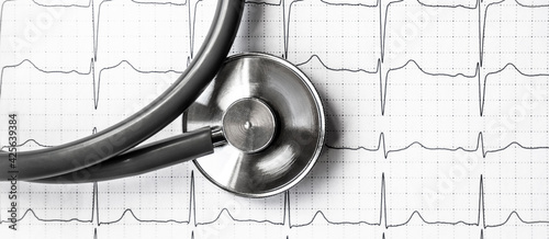 Photo of an electrocardiogram ECG or EKG printout with stethoscope. Medical health concept. Auscultation, listening to the heart with a stethoscope. Banner