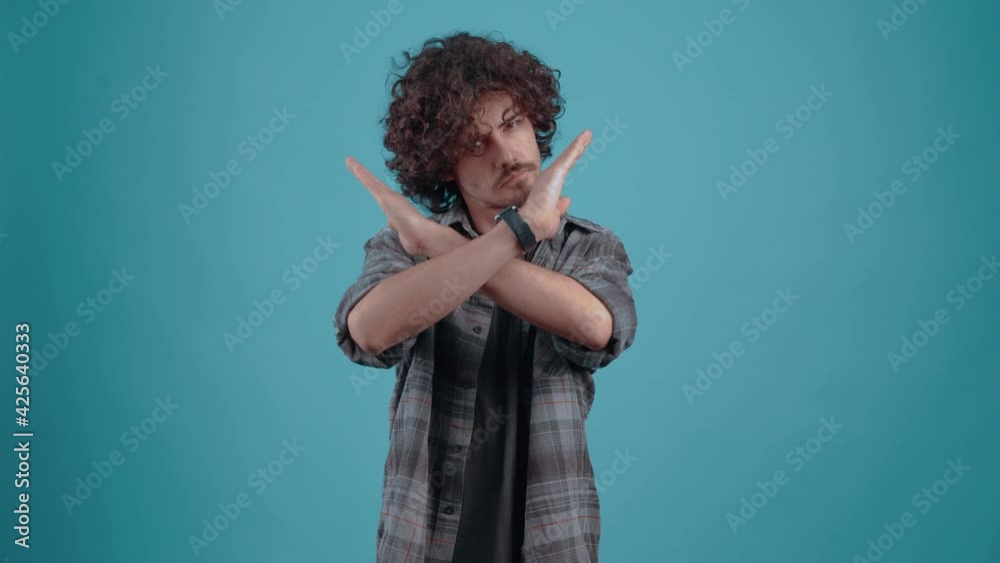 Responsible 20-year-old hipster with folded hands says stop in the studio on a turquoise background. The concept of people's lifestyle Responsible 20-year-old hipster with folded hands says stop in the studio on a turquoise background. The concept of people's lifestyle