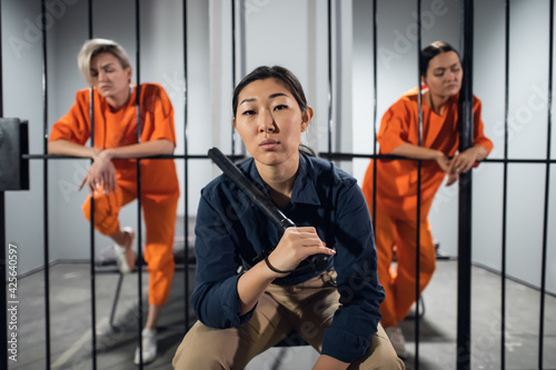 Asian women's prison. In the cell there are two young girls convicted of a criminal offense and a female warden in a guard's uniform photo