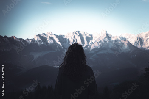 Beautiful young woman stands on background of mountains. Hiker girl inspired by view on Alps and beauty of nature outdoor. Adventure travel in Slovenia  Europe. Freedom  Leisure Activities Lifestyle