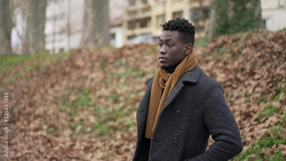 Pensive black man standing outside in cold winter season wearing scar and coat Pensive black man standing outside in cold winter season wearing scar and coat