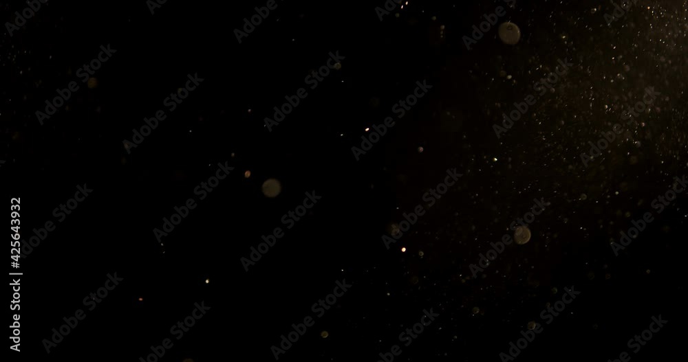 Golden glitter background in slow motion.  real dust particles floating in the air.  Universe gold dust with stars on black background.