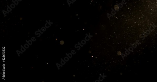 Golden glitter background in slow motion.  real dust particles floating in the air.  Universe gold dust with stars on black background.