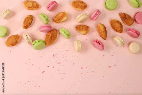 Fresh ruddy and colorful macaroons croissants on a light table with crumbs, Top view, place for text. Modern bakery concept, business card for advertising or invitation. Deliciousl breakfast,