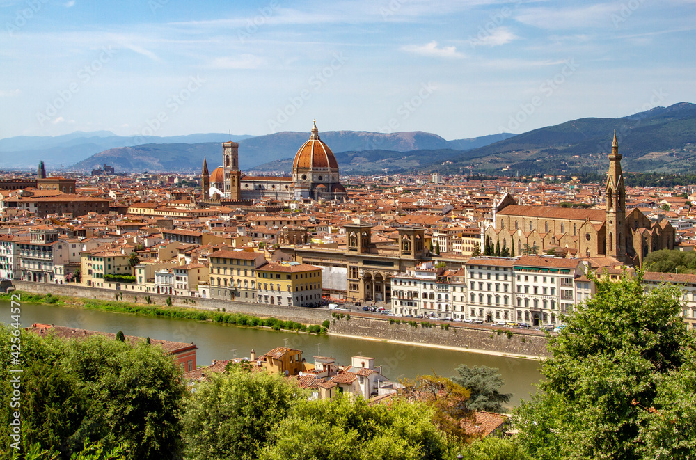 Top aerial panoramic view of Florence city with Duomo Cattedrale di Santa Maria del Fiore cathedral, buildings houses with orange red tiled roofs and hills range, blue sky white clouds, Tuscany, Italy
