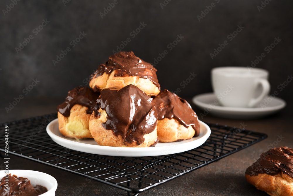 Profiteroles with vanilla cream and chocolate sauce with a cup of coffee on the kitchen table. Profiteroles with vanilla cream and chocolate sauce with a cup of coffee on the kitchen table.