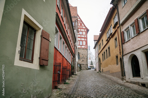 Medieval narrow street, colorful renaissance and gothic historical buildings, half-timbered houses, paving stone, autumn day, old town, Rothenburg ob der Tauber, Bavaria, Germany