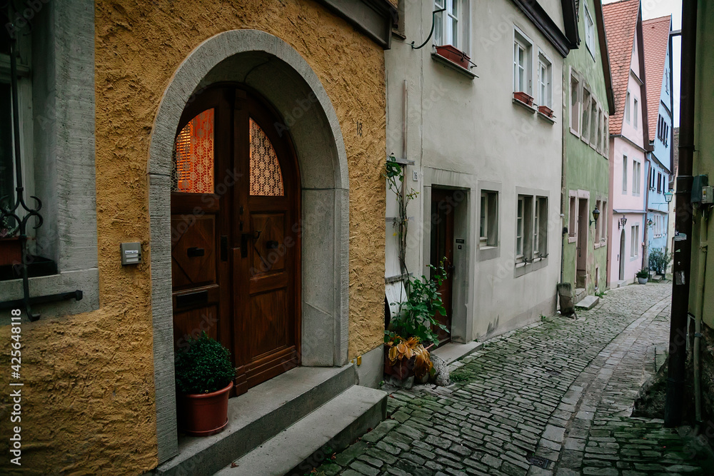 Medieval narrow street, colorful renaissance and gothic historical buildings, vintage wooden doors, paving stone, autumn day, old town, Rothenburg ob der Tauber, Bavaria, Germany