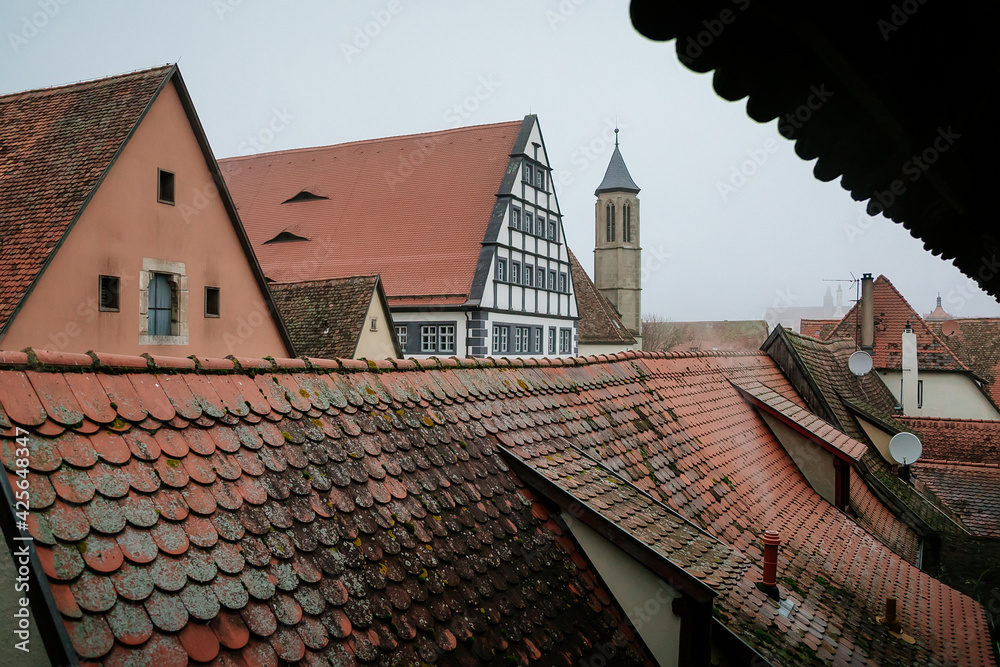 Red tiled roofs, stone gothic towers, fog, renaissance and gothic historical buildings, old town, medieval street, half-timbered houses, Rothenburg ob der Tauber, Bavaria, Germany