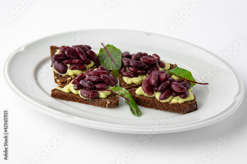 Rye bread bruschetta with vegetarian pate, red beans and greens. Banquet festive dishes. Gourmet restaurant menu. White background.