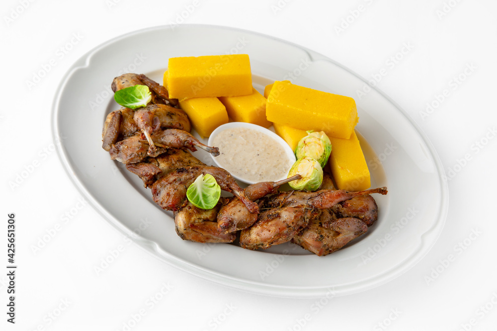 Grilled quails in a sauce with vegetables and herbs. Gentle, diet poultry meat. Banquet festive dishes. Gourmet restaurant menu. White background.