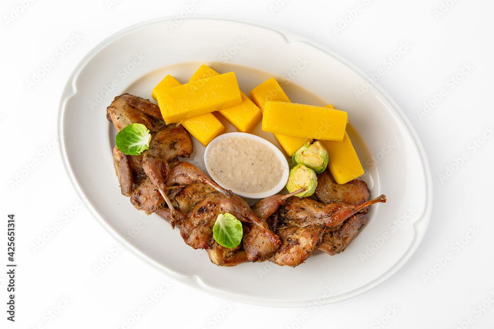 Grilled quails in a sauce with vegetables and herbs. Gentle, diet poultry meat. Banquet festive dishes. Gourmet restaurant menu. White background.