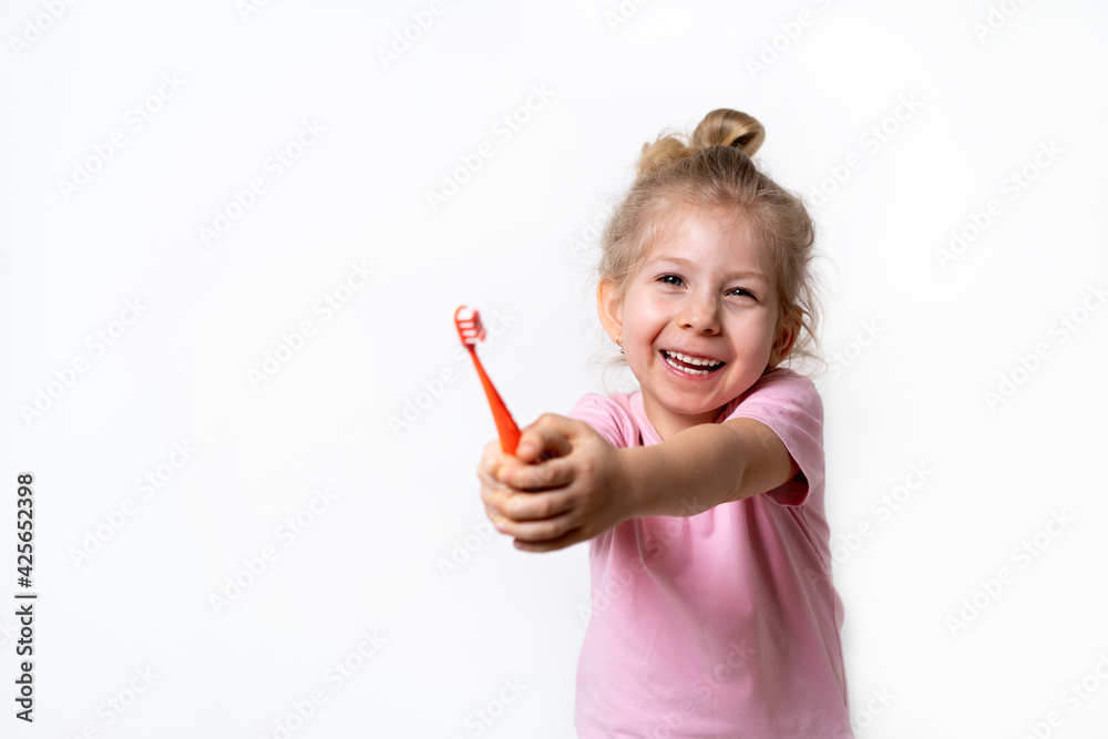 a cheerful little blonde girl smiles and holds a toothbrush on a white background, a place for text, the concept of caring for children's baby teeth and oral hygiene a cheerful little blonde girl smiles and holds a toothbrush on a white background, a place for text, the concept of caring for children's baby teeth and oral hygiene