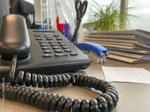 Gray and black business wired phone with receiver, dial and large display in the business office environment © Aliaksandra