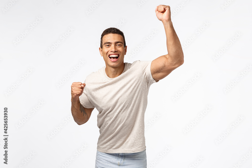 Man lift hand up in hooray motion, cheering for favorite sports team.  Handsome young strong guy fist pump and smiling, encourage friend score  goal, rooting for someone, placed bet white background Stock