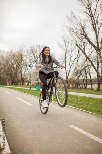 one young woman, riding bicycle Wheelie style.