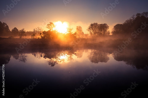A beautiful river morning with mist and sun light. Springtime scenery of river banks in Northern Europe. Warm, colorful look. © dachux21