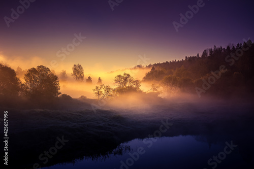 A beautiful river morning with mist and sun light. Springtime scenery of river banks in Northern Europe. Warm  colorful look.