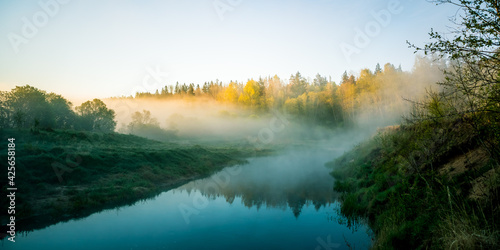 A beautiful river morning with mist and sun light. Springtime scenery of river banks in Northern Europe. Warm, colorful look. © dachux21