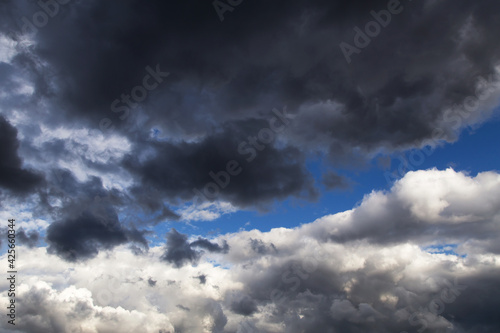 Thunderstorm clouds texture. Epic storm sky with dark grey and white cumulus clouds against blue sky background