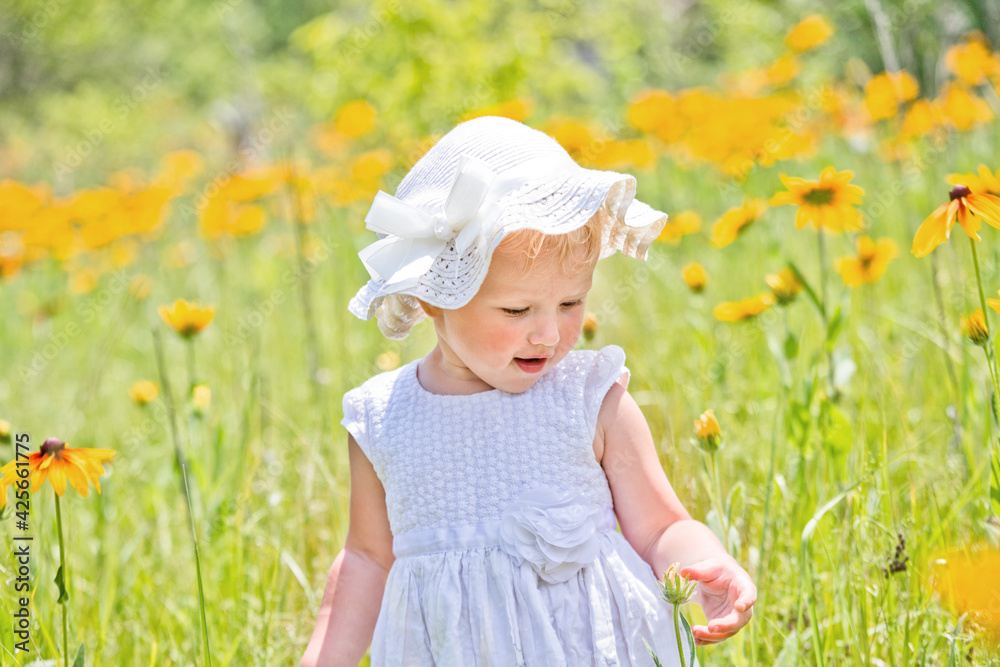 Portrait of beautiful little girl on background of yellow flowers in a meadow. happy childhood in nature. Walking while quarantine away from people Portrait of beautiful little girl on background of yellow flowers in a meadow. happy childhood in nature. Walking while quarantine away from people
