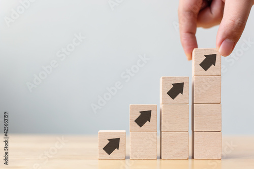 Ladder career path for business growth success process concept.Hand arranging wood block stacking as step stair with arrow up