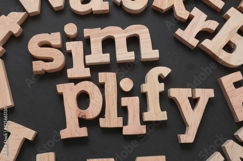 Simplify, text words typography written with wooden letter on black background, life and business motivational inspirational
