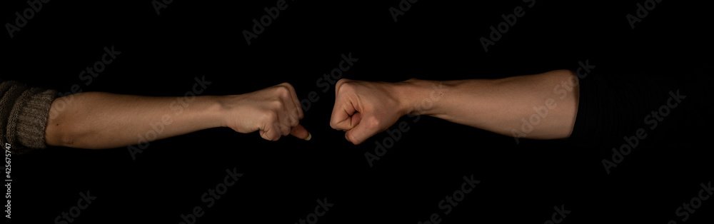 Man and woman fist to fist isolated on the black background. Panoramic shot. Copy space for text message. Panorama banner. Man and woman fist to fist isolated on the black background. Panoramic shot. Copy space for text message. Panorama banner.
