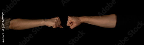 Man and woman fist to fist isolated on the black background. Panoramic shot. Copy space for text message. Panorama banner.