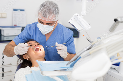 Portret of male dentist and woman patient sitting in medical chair during checkup at dental clinic office