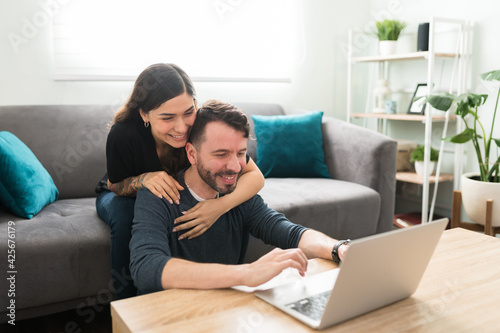 Married couple hugging while using a laptop on the sofa