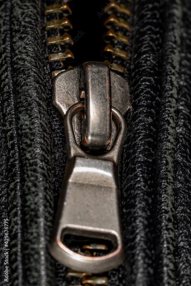 Detail of locking zipper on black leather jacket. Close up macro local focus shot. Vertical macro photography view. Detail of locking zipper on black leather jacket. Close up macro local focus shot. Vertical macro photography view.