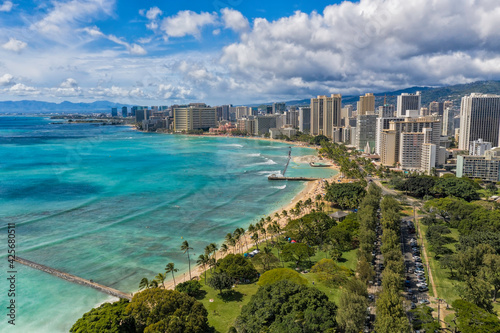 Aerial view of Waikiki skyline neighborhood and city park next to Queens Beach in Honolulu, Hawaii