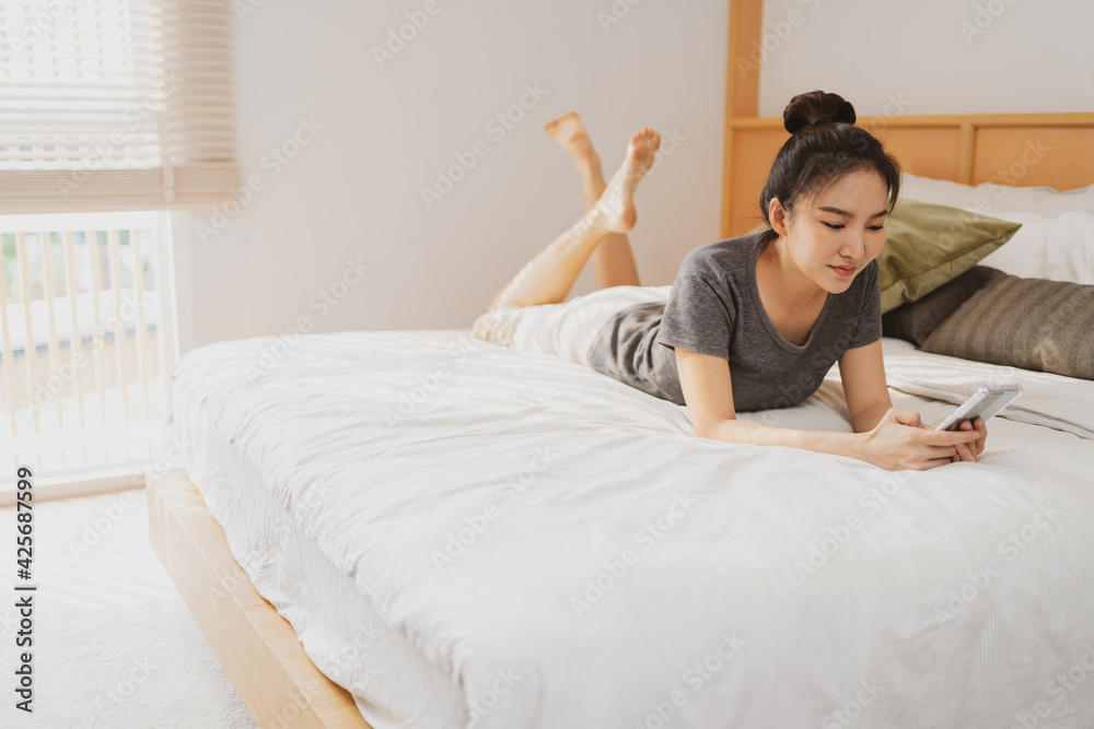 happy Young asian woman holding cellphone in bed happy Young asian woman holding cellphone in bed